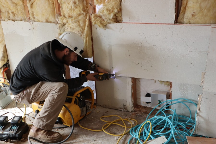 A technician does an in-wall electrical wiring installation.