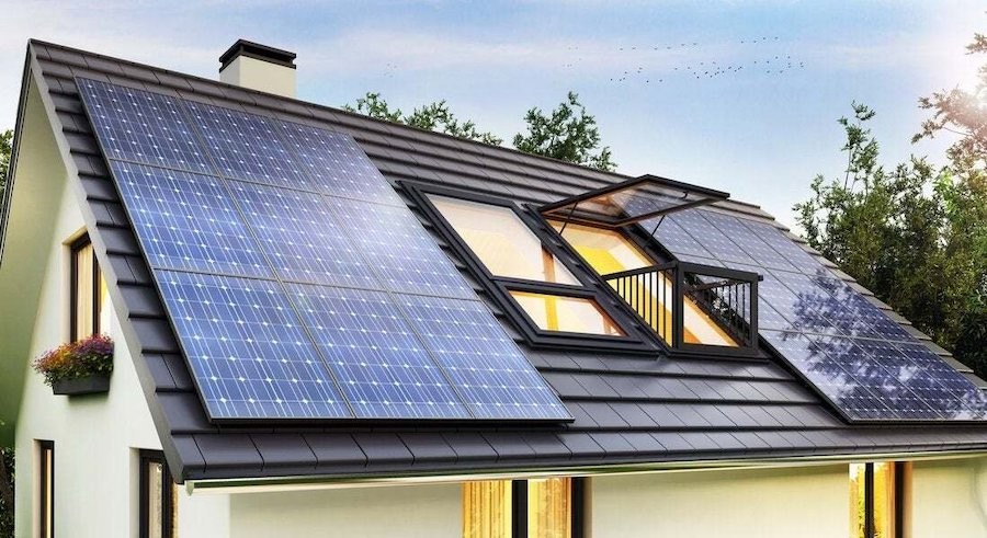 A modern home with a pitched tile roof covered with solar panels. 