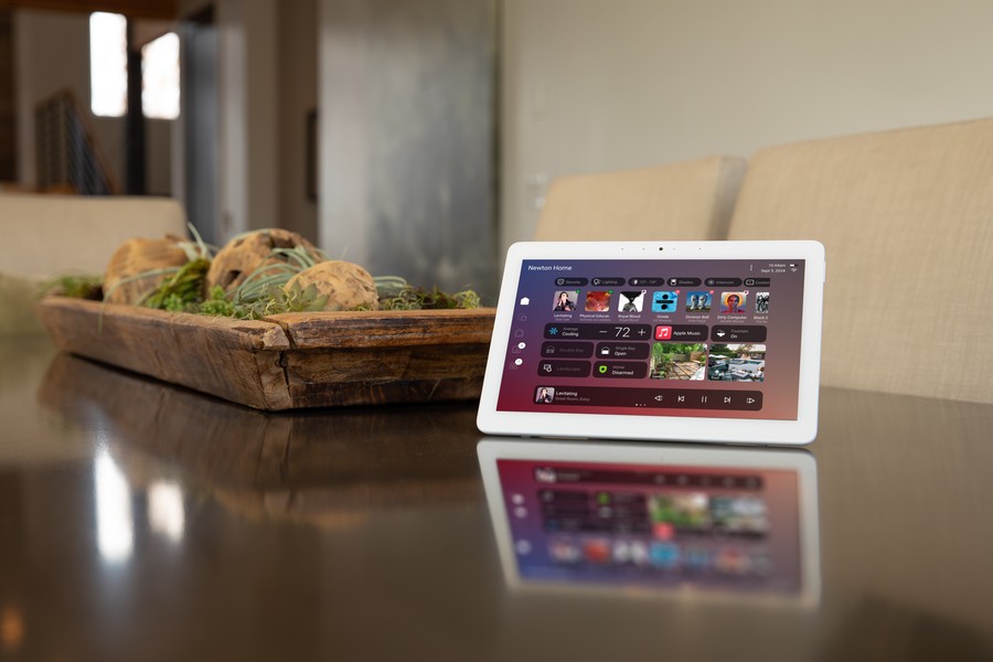 Tablet on dining table showing Control4 X4 dashboard for music, climate, and security next to wood centerpiece.