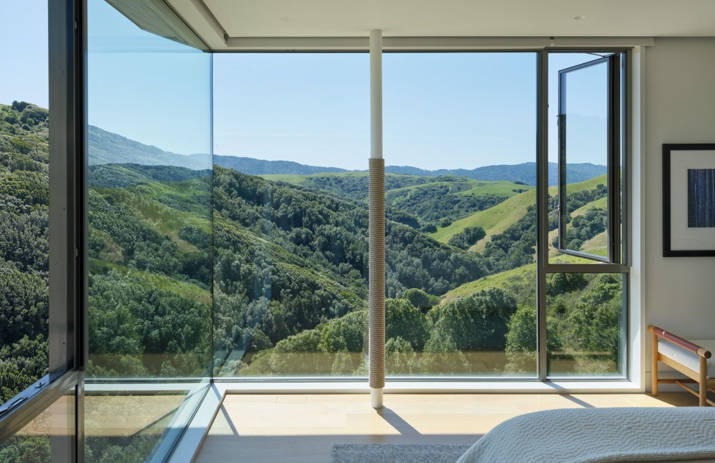 Bedroom with a corner glass window looking across the valley.