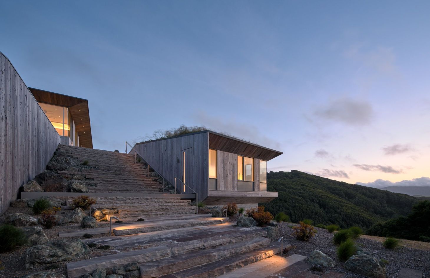 Stone entry stairs and landscape lighting at dusk, with the estate running on stored solar power after sunset.