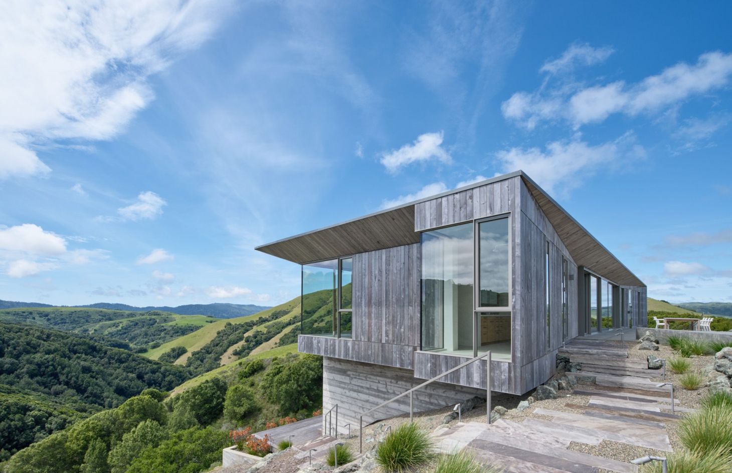 Cantilevered wood-clad wing of the estate overlooking the valley, built to run fully off-grid on solar and battery storage.