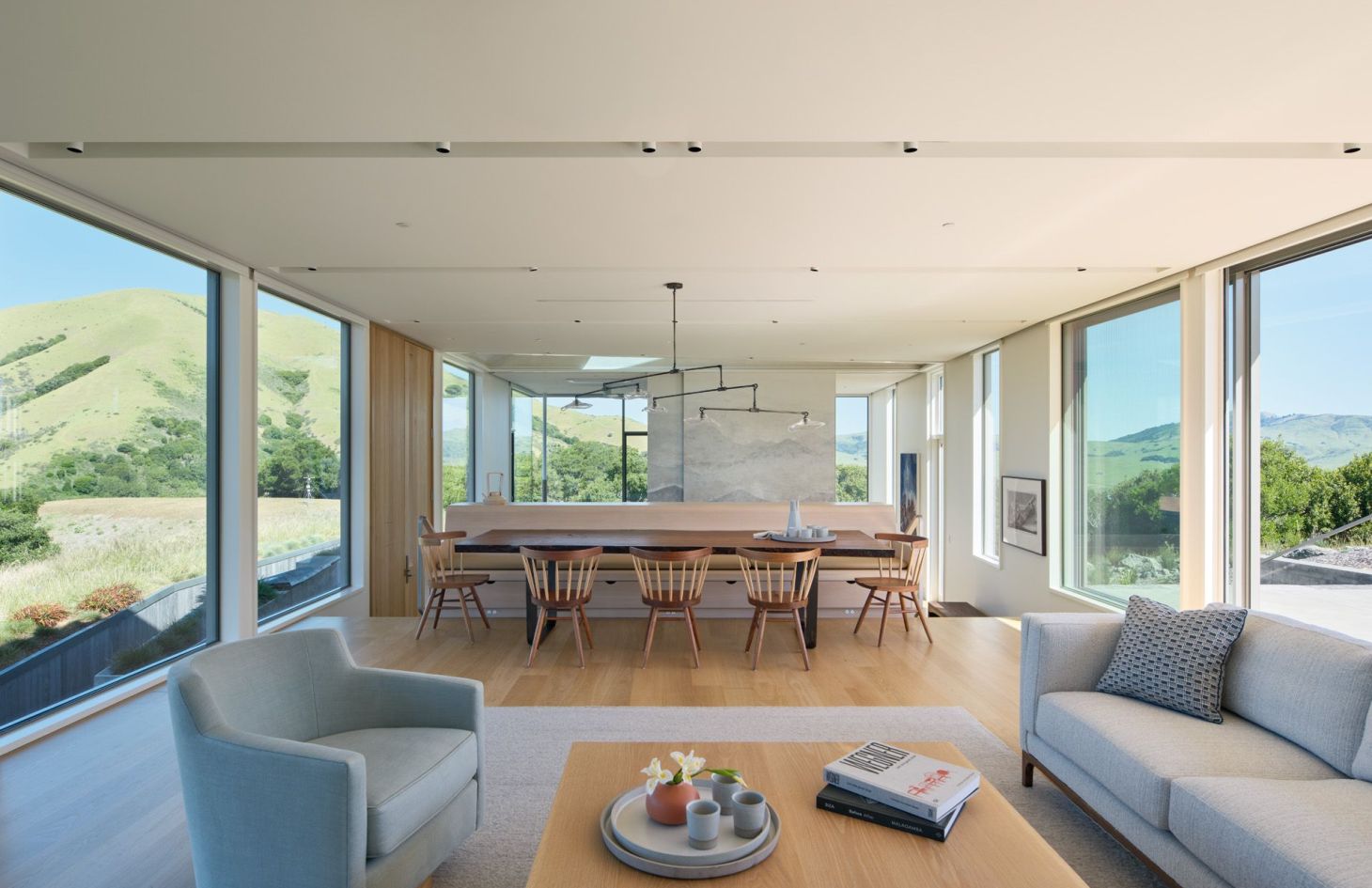 Open living and dining area with walls of glass looking out to the surrounding hills.