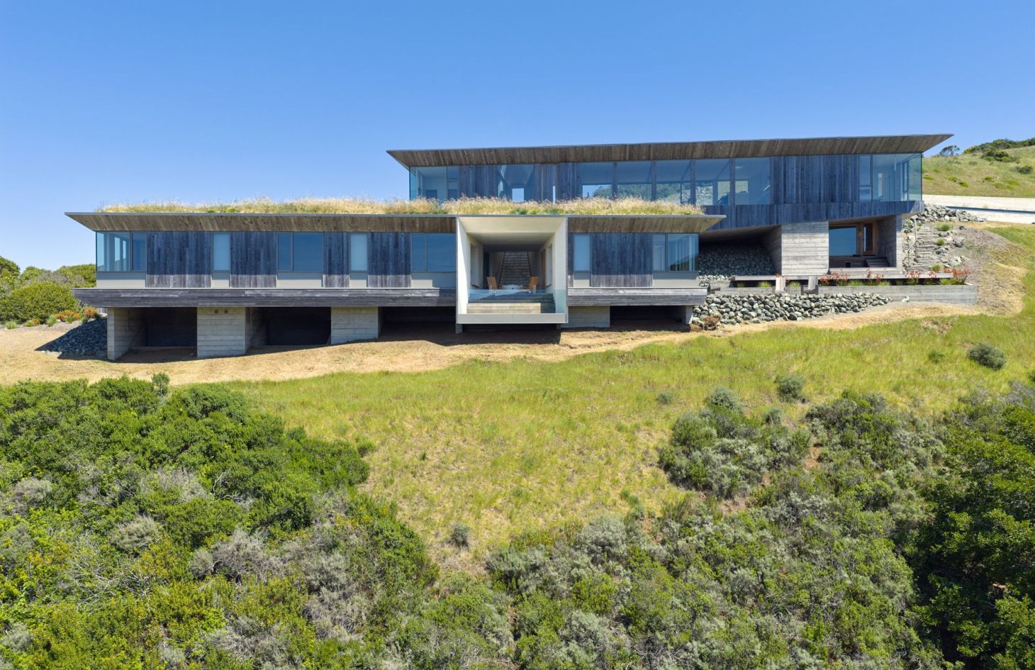 Front exterior of the off-grid estate, with a planted green roof and wood-clad wings set into the Marin County hills.