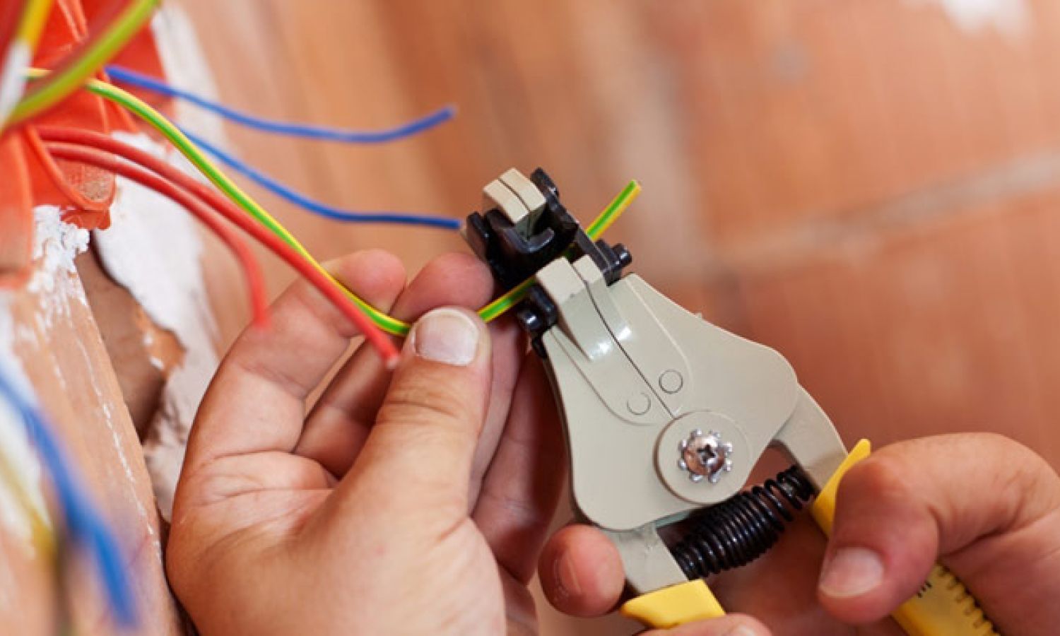 Close-up of electrician using precision wire stripping tool to prepare electrical wiring for safe and professional installation