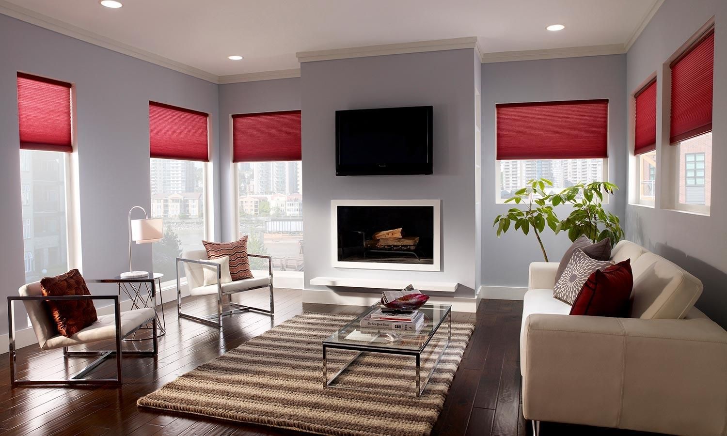 Contemporary living room with Lutron cellular shades, bright red accents, and a fireplace.